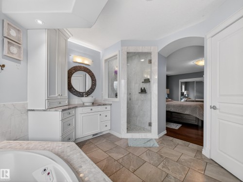 Spacious bathroom featuring a corner soaking tub with mosaic tile surround, a glass-enclosed shower with tiled walls, and a vanity with a vessel sink and abundant white cabinetry - 1062 Tory Road, Edmonton, AB - Indoor Photo Showing Bathroom