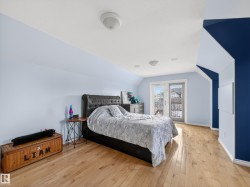 Attic bedroom featuring light wood-finish flooring and a multi-tone wall design - 