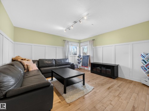 Room featuring wood-finish flooring, white board and batten wall detailing, and light green painted walls - 1062 Tory Road, Edmonton, AB - Indoor Photo Showing Living Room