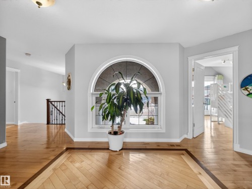 Grand foyer featuring an arched transom window, light wood-finish flooring with a contrasting inlay, white trim, and a semi-flush mount ceiling light - 1062 Tory Road, Edmonton, AB - Indoor Photo Showing Other Room