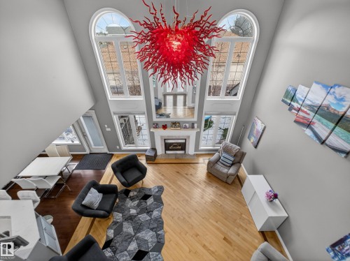Two-story living area featuring a prominent red chandelier and light wood-finish flooring - 1062 Tory Road, Edmonton, AB - Indoor With Fireplace