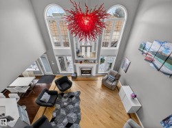 Two-story living area featuring a prominent red chandelier and light wood-finish flooring - 