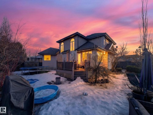 Two-story stucco exterior featuring arched windows on the upper level, a multi-level deck, and a fenced perimeter - 1062 Tory Road, Edmonton, AB - Outdoor With Deck Patio Veranda