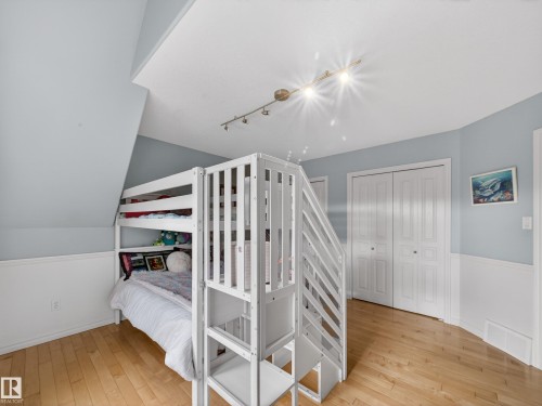 Light wood-finish flooring complements the wainscoting and light blue walls - 1062 Tory Road, Edmonton, AB - Indoor Photo Showing Bedroom