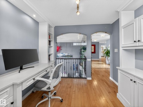 Dedicated workspace featuring built-in white cabinetry, integrated shelving, and wood-finish flooring - 1062 Tory Road, Edmonton, AB - Indoor Photo Showing Office
