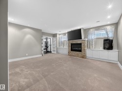 Spacious room featuring carpet flooring, recessed lighting, and a stone-clad fireplace - 
