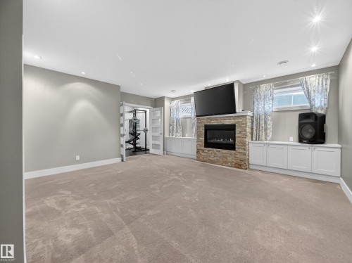 Spacious room featuring carpet flooring, recessed lighting, and a stone-clad fireplace - 1062 Tory Road, Edmonton, AB - Indoor Photo Showing Living Room With Fireplace