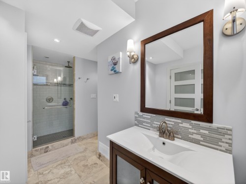 Bathroom vanity with an integrated sink, brushed nickel faucet, and a mosaic tile backsplash - 1062 Tory Road, Edmonton, AB - Indoor Photo Showing Bathroom