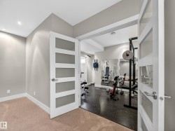 Dedicated fitness room featuring dark flooring, recessed lighting, and mirrored wall accents - 