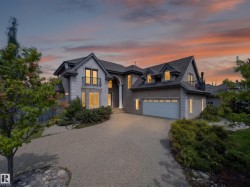 Stone-clad exterior featuring multiple dormer windows, a prominent entrance with columns, and a two-car garage - 