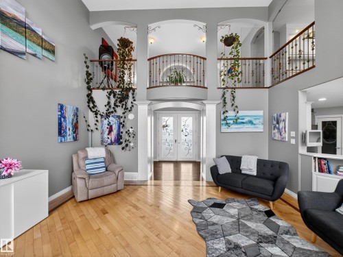 Two-story foyer featuring hardwood flooring, a decorative iron and wood staircase, arched doorways, and double entry doors with etched glass - 1062 Tory Road, Edmonton, AB - Indoor Photo Showing Other Room