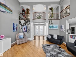 Two-story foyer featuring hardwood flooring, a decorative iron and wood staircase, arched doorways, and double entry doors with etched glass - 