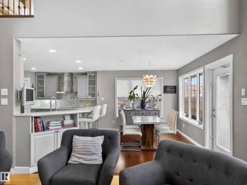 Open-concept kitchen and dining area featuring light gray cabinetry, a mosaic tile backsplash, and a breakfast bar with seating - 1062 Tory Road, Edmonton, AB - Indoor Photo Showing Living Room