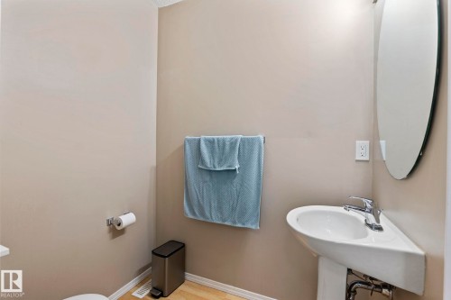 Corner pedestal sink with chrome faucet, complemented by an oval wall-mounted mirror - 92 4350 23 Street, Edmonton, AB - Indoor Photo Showing Bathroom