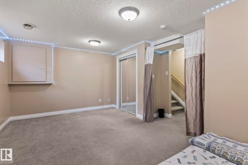 Carpeted room featuring neutral wall paint, white baseboards, and a built-in closet with mirrored sliding doors - 92 4350 23 Street, Edmonton, AB - Indoor