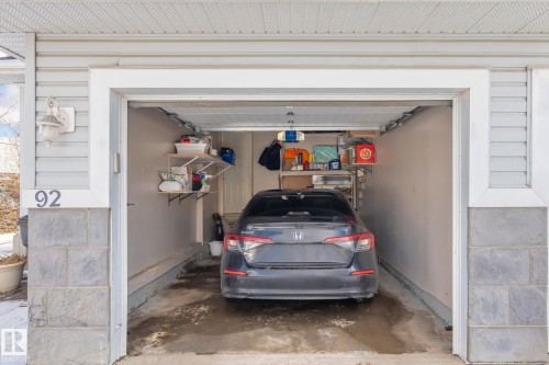 Attached garage with a light gray siding exterior and gray stacked stone veneer - 92 4350 23 Street, Edmonton, AB - Indoor Photo Showing Garage