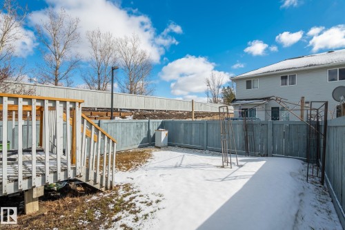 Spacious backyard featuring a wooden deck with railing, full perimeter fencing, and a two-story exterior with siding and multiple windows - 92 4350 23 Street, Edmonton, AB - Outdoor