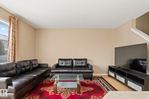 Living area featuring light beige walls, wood-finish flooring, a window with vertical blinds, and a built-in media console - 92 4350 23 Street, Edmonton, AB - Indoor Photo Showing Living Room