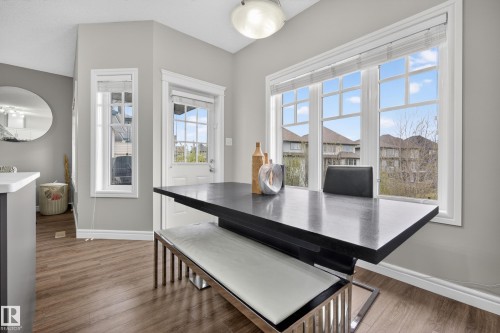 Bright dining area with large pane windows, wood-finish flooring, and a modern ceiling light fixture - 2146 Austin Link Link, Edmonton, AB - Indoor