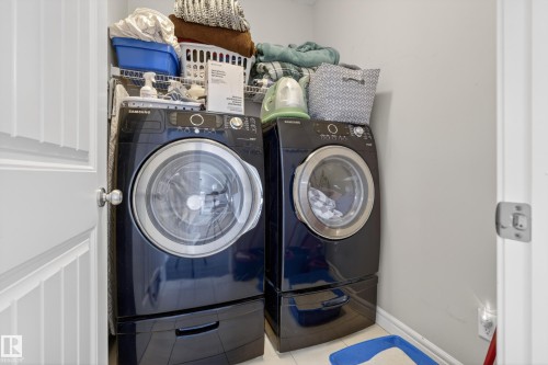 Dedicated laundry area featuring front-loading washer and dryer units with pedestal bases - 2146 Austin Link Link, Edmonton, AB - Indoor Photo Showing Laundry Room