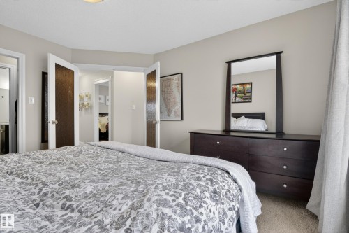 Bedroom featuring neutral wall paint, carpeted flooring, a ceiling-mounted light fixture, and a dark wood dresser with a matching mirror - 2146 Austin Link Link, Edmonton, AB - Indoor Photo Showing Bedroom