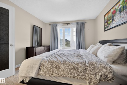 Bedroom with light neutral wall paint, a window featuring light-filtering curtains, and textured carpeting - 2146 Austin Link Link, Edmonton, AB - Indoor Photo Showing Bedroom