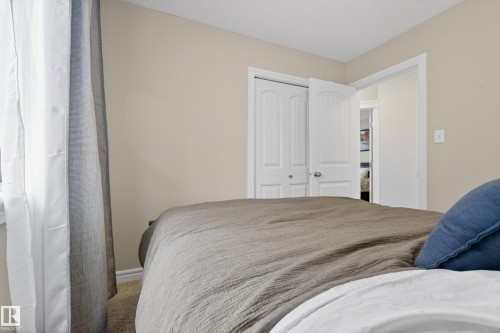 Bedroom featuring neutral wall paint, textured carpeting, and white bi-fold closet doors - 2146 Austin Link Link, Edmonton, AB - Indoor Photo Showing Bedroom