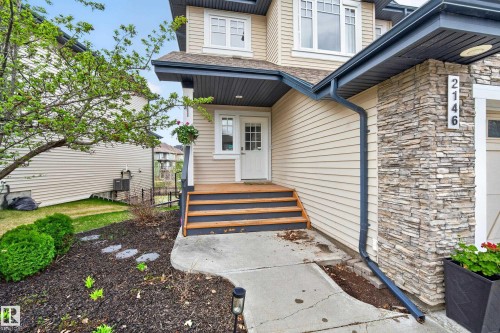 Exterior featuring stacked stone accents, horizontal siding, and a covered entry with wood-finish steps - 2146 Austin Link Link, Edmonton, AB - Outdoor