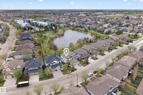 Aerial perspective showcasing a residential neighborhood with a central pond and surrounding green space - 2146 Austin Link Link, Edmonton, AB - Outdoor With View