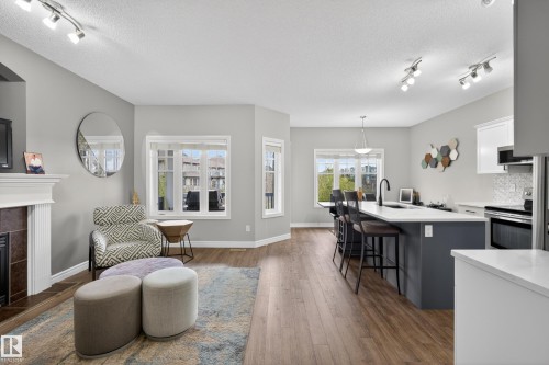 Open-concept living space with wood-finish flooring - 2146 Austin Link Link, Edmonton, AB - Indoor With Fireplace
