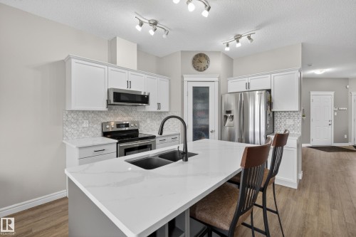 Central kitchen island with an undermount double-basin sink and matte black faucet - 2146 Austin Link Link, Edmonton, AB - Indoor Photo Showing Kitchen With Double Sink With Upgraded Kitchen