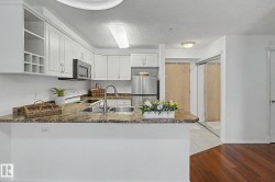 Kitchen featuring white cabinetry, stone-finish countertops, stainless steel appliances, and a double basin sink with a gooseneck faucet - 