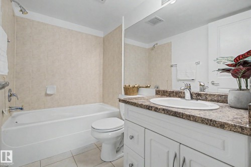 Bathroom featuring a white vanity with panel cabinetry and a speckled countertop - 213 17404 64 Avenue, Edmonton, AB 
