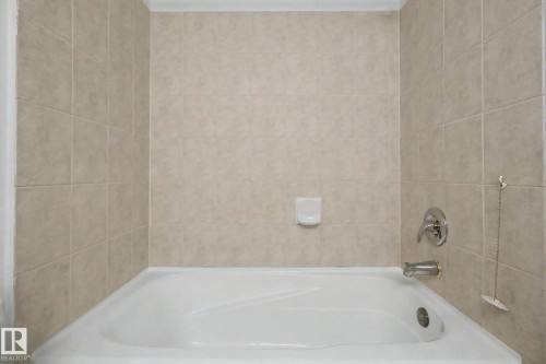 White alcove bathtub with light-toned square wall tiles, chrome fixtures, and a soap dish - 213 17404 64 Avenue, Edmonton, AB 
