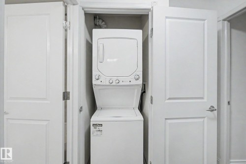 Dedicated laundry closet featuring a stackable washer and dryer unit - 213 17404 64 Avenue, Edmonton, AB 