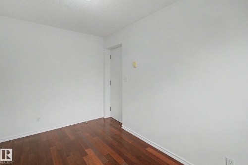Wood-finish flooring with white baseboards, bright white walls, and a recessed ceiling light - 213 17404 64 Avenue, Edmonton, AB 