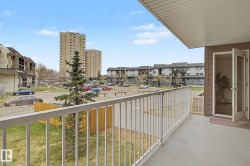 Private balcony with concrete flooring, white metal railing, and a glass-paneled door - 