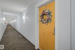 Building corridor featuring a light-toned entry door with a decorative wreath - 