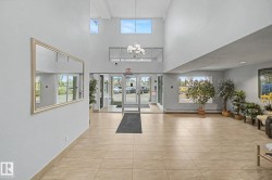 Bright common area featuring high ceilings, upper-level windows, and a multi-light chandelier - 