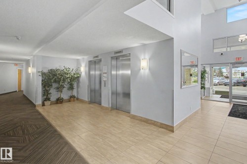 Contemporary lobby with dual stainless steel elevators, recessed lighting, and large format tiled flooring - 213 17404 64 Avenue, Edmonton, AB 