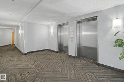 Two stainless steel elevators serving a hallway with geometric patterned carpet flooring - 