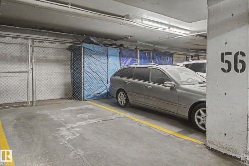 Underground parking garage featuring concrete flooring, overhead fluorescent lighting, and a designated parking stall marked with yellow lines - 213 17404 64 Avenue, Edmonton, AB 