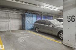Underground parking garage featuring concrete flooring, overhead fluorescent lighting, and a designated parking stall marked with yellow lines - 