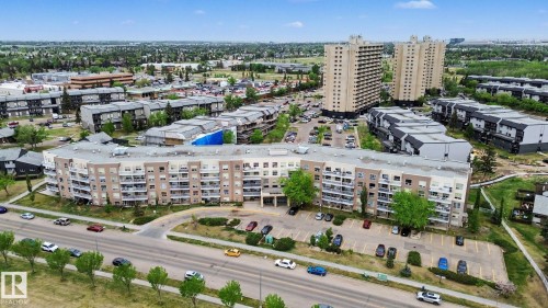Contemporary low-rise building featuring a curved architectural design, multiple private balconies, ample surface parking, and manicured green spaces - 213 17404 64 Avenue, Edmonton, AB 