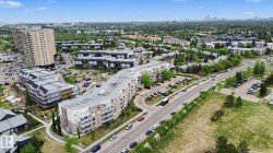 Aerial perspective showcasing the surrounding neighborhood, featuring multiple multi-story residential buildings, ample surface parking, mature trees, and nearby roadways - 