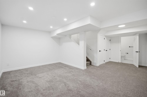 Spacious lower-level room featuring light gray carpeting, white walls, and recessed lighting - 1706 37 Street, Edmonton, AB - Indoor