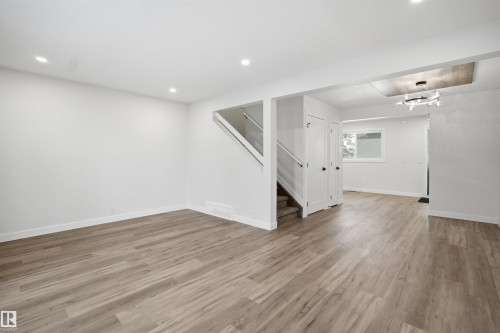 Spacious open-concept living area featuring wood-finish flooring, recessed lighting, and a modern chandelier - 1706 37 Street, Edmonton, AB - Indoor Photo Showing Other Room