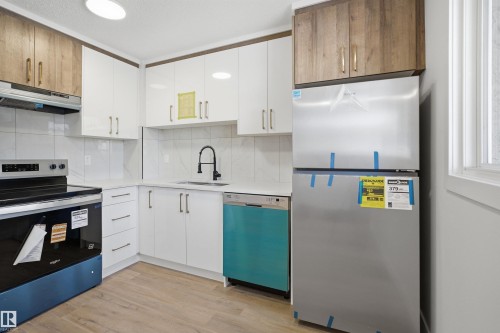 Modern kitchen featuring white cabinetry complemented by wood-finish upper cabinets - 1706 37 Street, Edmonton, AB - Indoor Photo Showing Kitchen