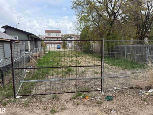 Fenced lot with an open-field area, featuring a metal gate and partial fencing - 9345 103A Avenue, Edmonton, AB 