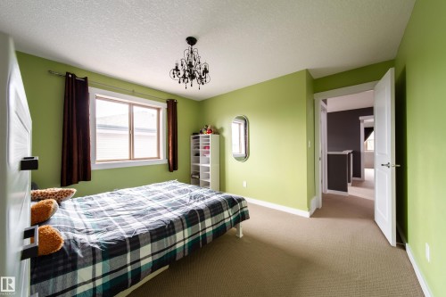 Room featuring light green walls, a single window with brown curtains, a black chandelier, and neutral-toned carpeting - 2016 125 Street, Edmonton, AB - Indoor Photo Showing Bedroom
